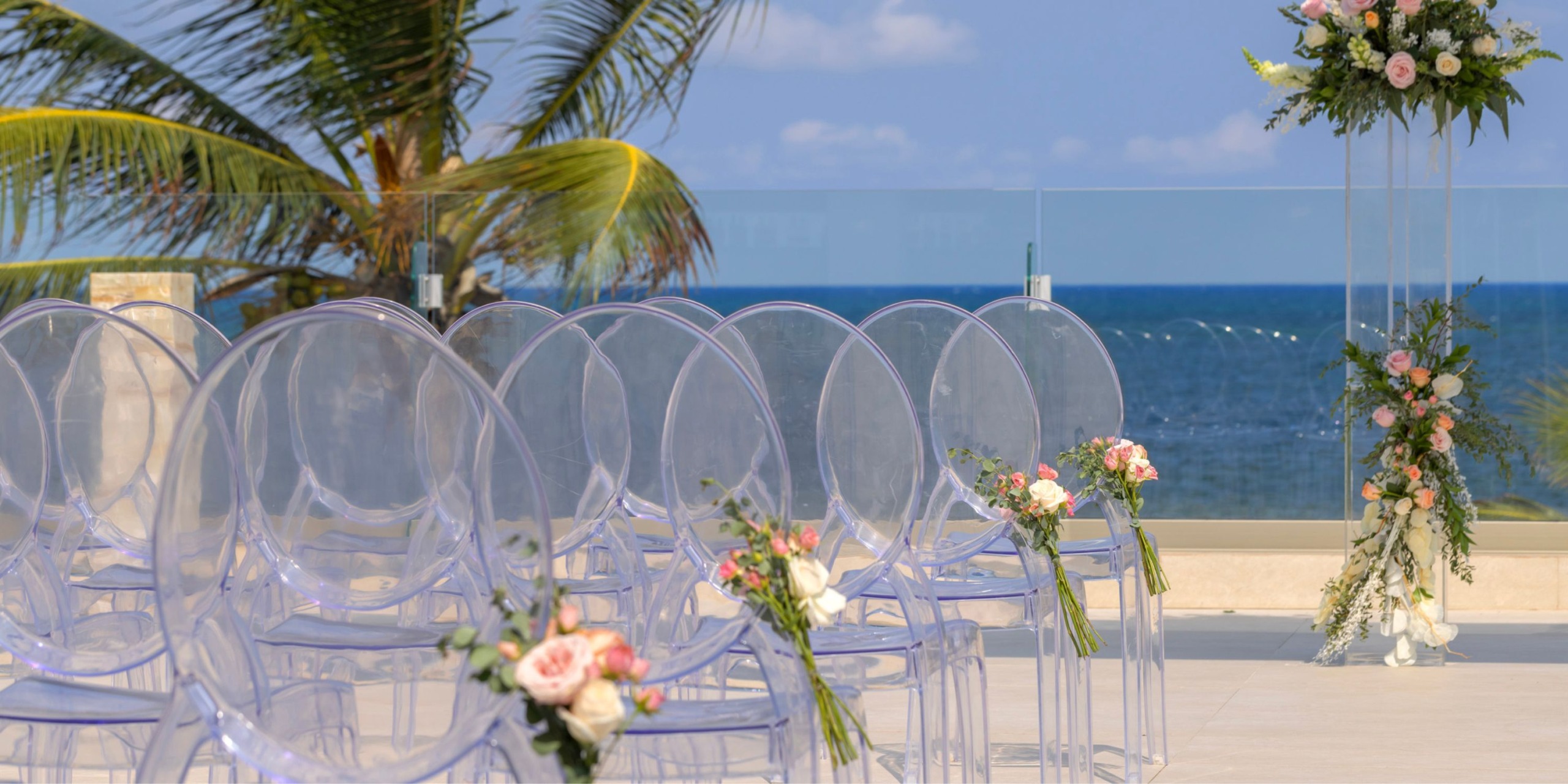Transparent chairs adorned with floral decorations enhance the charm of a destination wedding at Royalton Splash Riviera Cancun.