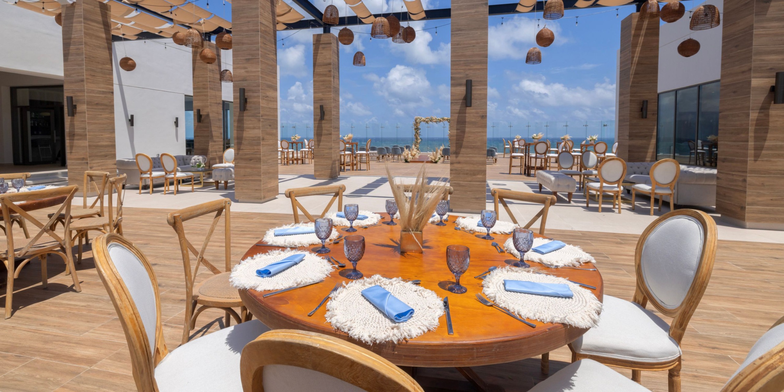 The dining area at Royalton Splash Riviera Cancun is beautifully arranged with elegantly set tables and captivating hanging lights, creating an enchanting atmosphere perfect for a destination wedding.
