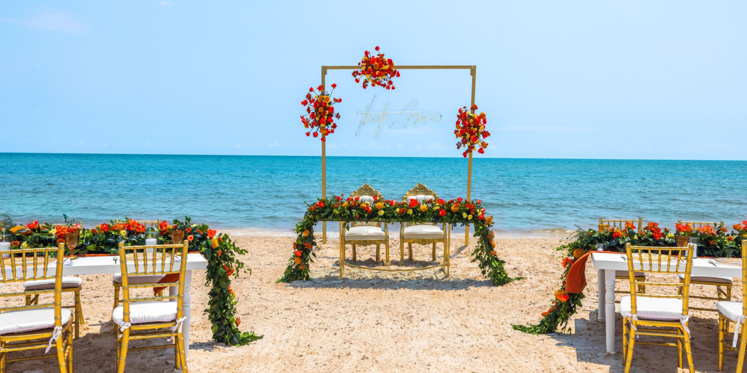 Experience a beachfront wedding at the Royalton Splash Riviera Cancun, complete with a flower-decorated arch, chairs, and tables on the sand, all facing the stunning ocean.