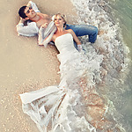 Couple sitting on the beach in their beach wedding attire
