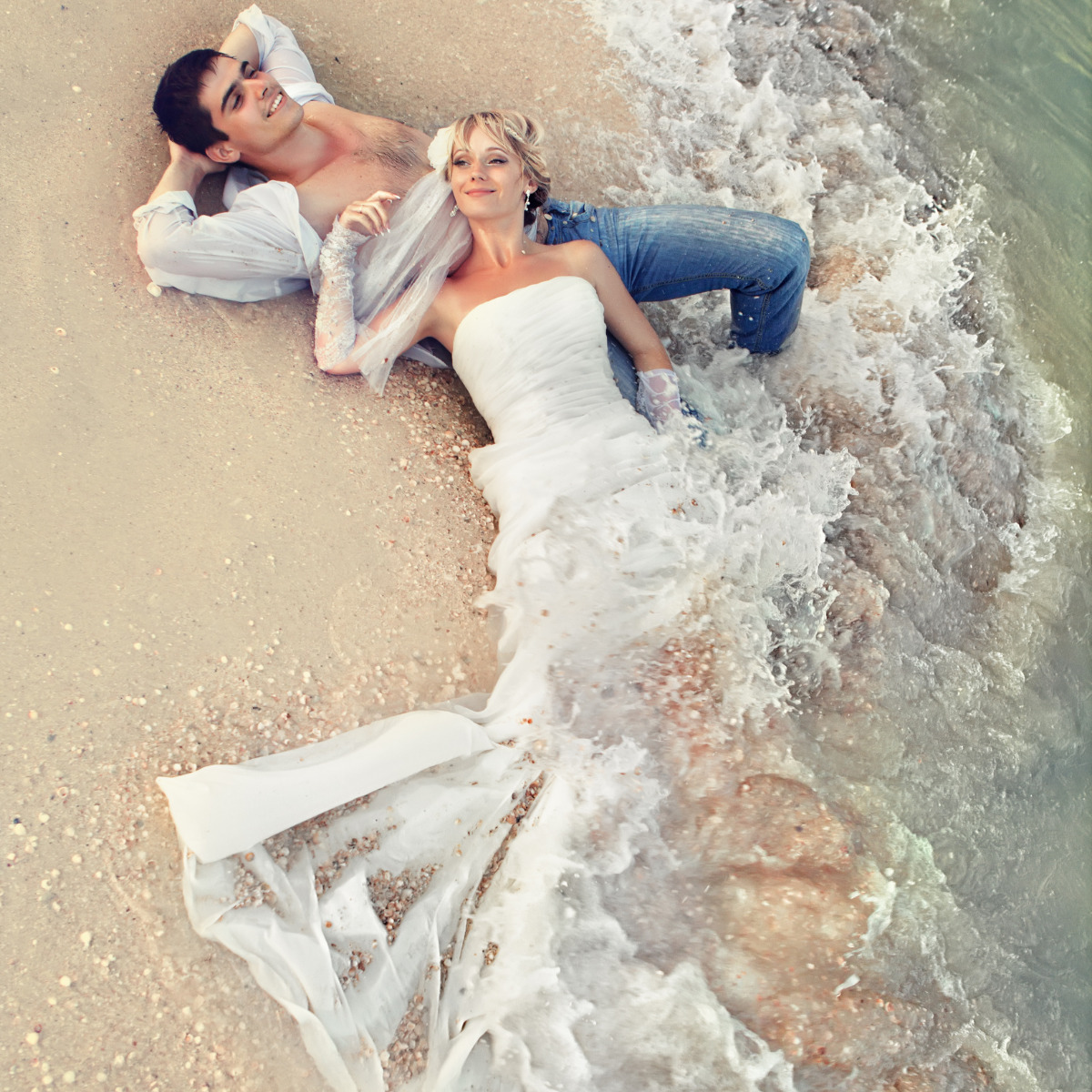 Couple sitting on the beach in their beach wedding attire