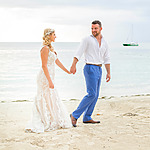 Gorgeous bride and groom hold hands on the beach, destination wedding pros and cons