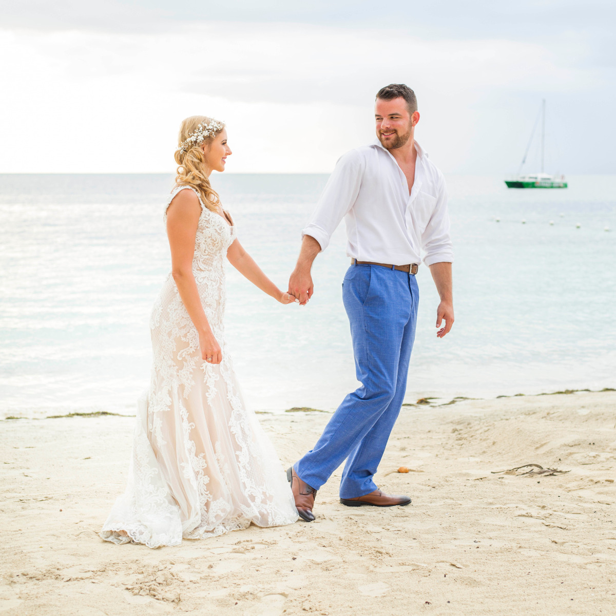 Gorgeous bride and groom hold hands on the beach, destination wedding pros and cons
