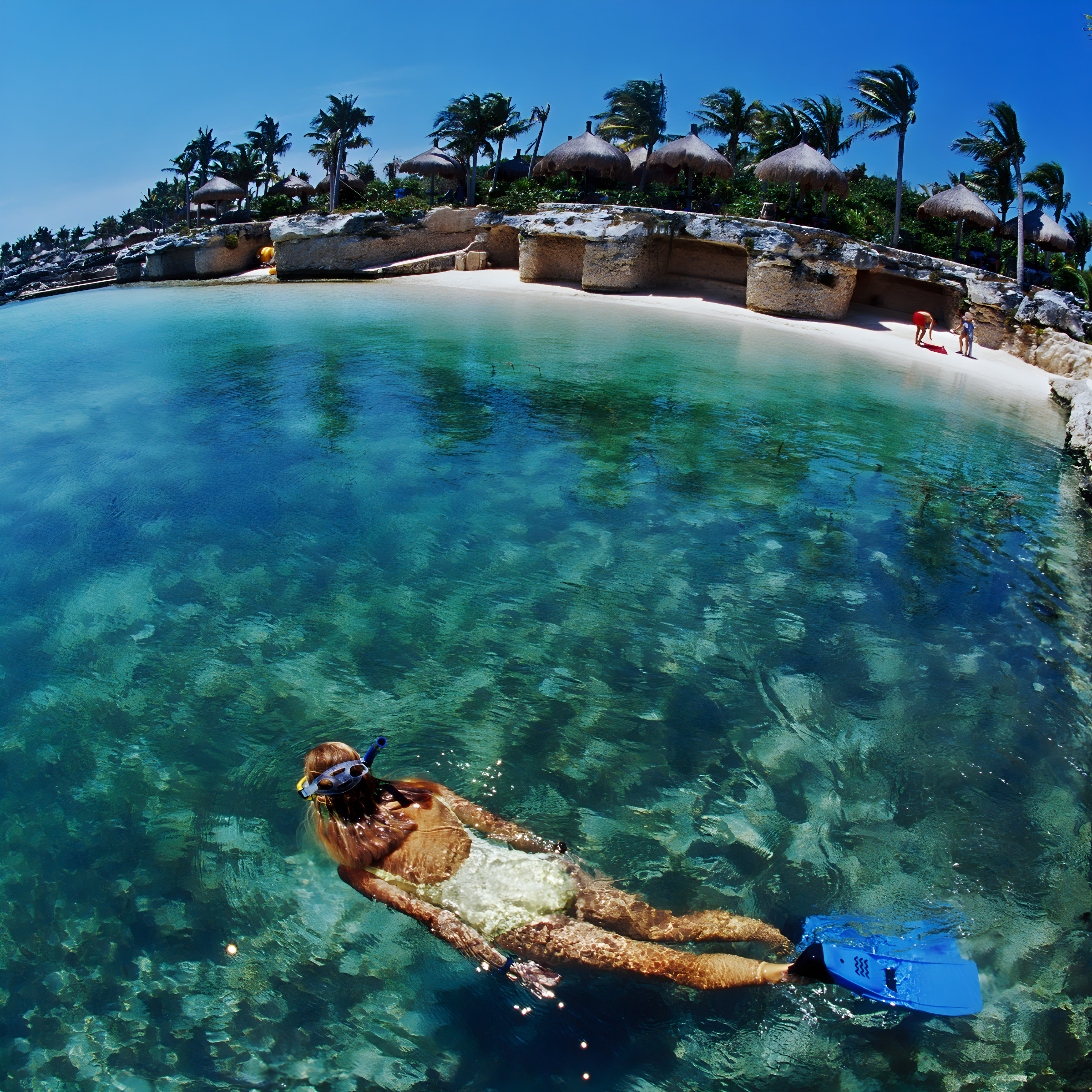 A woman snorkeling in clear blue water near a sandy shore with tropical huts and palm trees, enjoying a destination wedding.