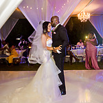 A bride and groom share a close dance at their destination wedding reception, surrounded by guests under an elegant, lit tent.
