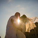 A couple at their destination wedding shares a tender moment with the sun flaring between them, creating a silhouette effect.