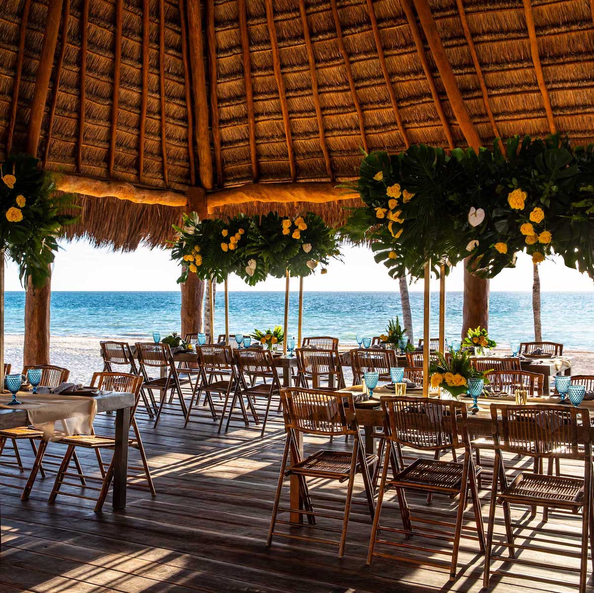 A destination wedding reception set up on the beach with tables and chairs, offering various wedding packages prices.