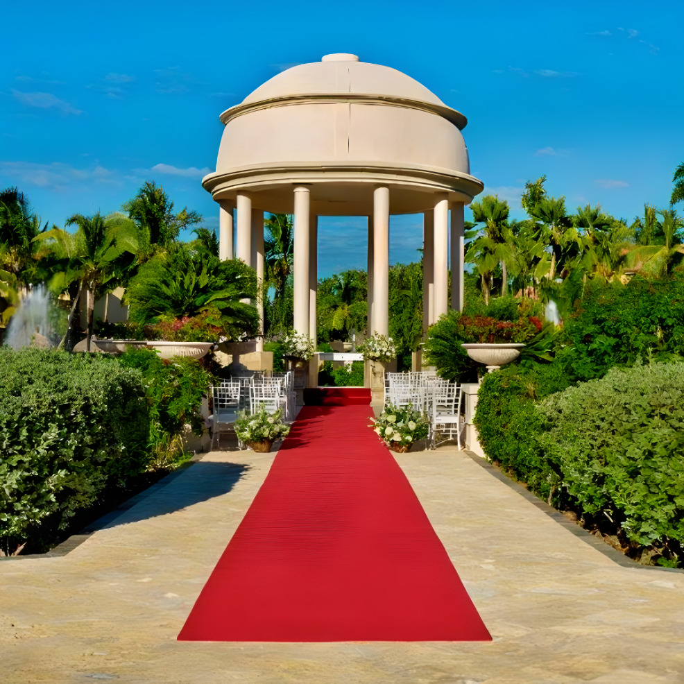 A destination wedding with a red carpet in front of a gazebo.