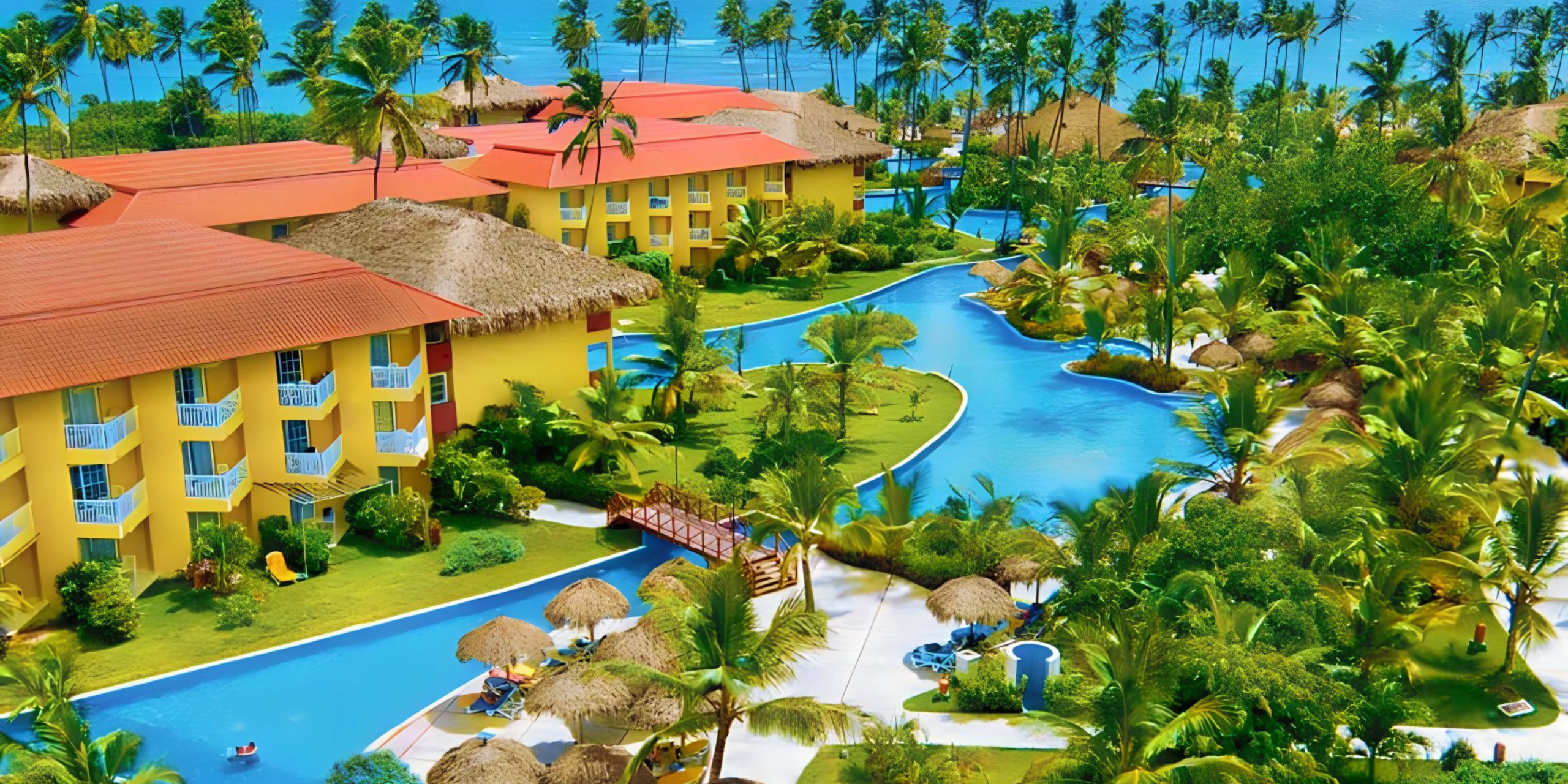 Aerial view of Jewel Punta Cana, a tropical resort destination for weddings, with red-roofed buildings surrounded by winding blue pools and lush greenery.