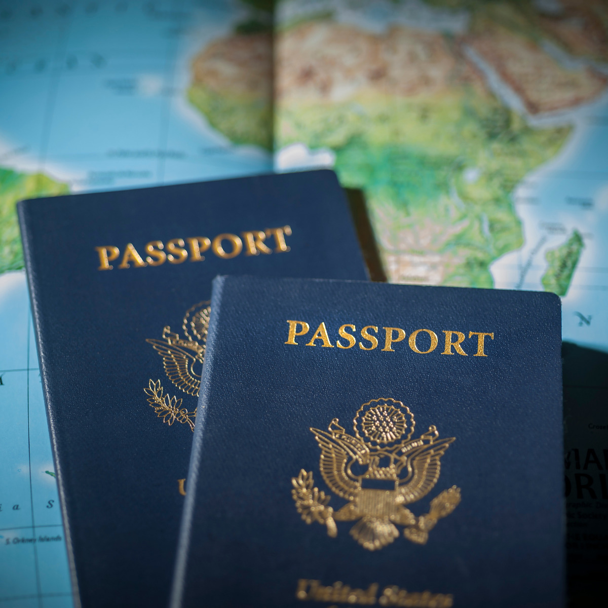 Two U.S. passports marked for renewal on a world map, highlighting travel and international geography.