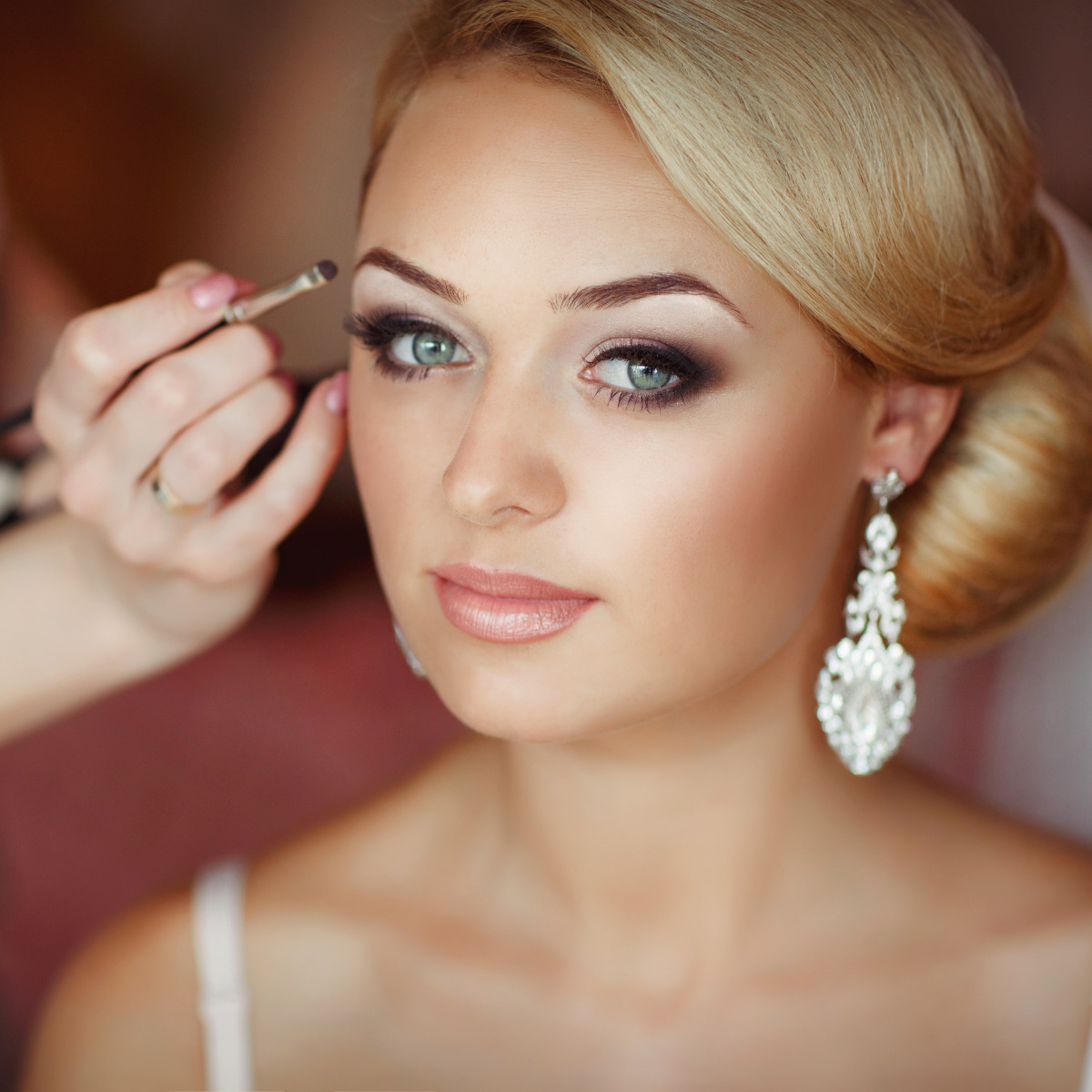 A bride getting her makeup done by a makeup artist for her wedding.