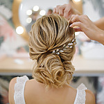 A bride getting her hair styled for her wedding by a hairstylist.