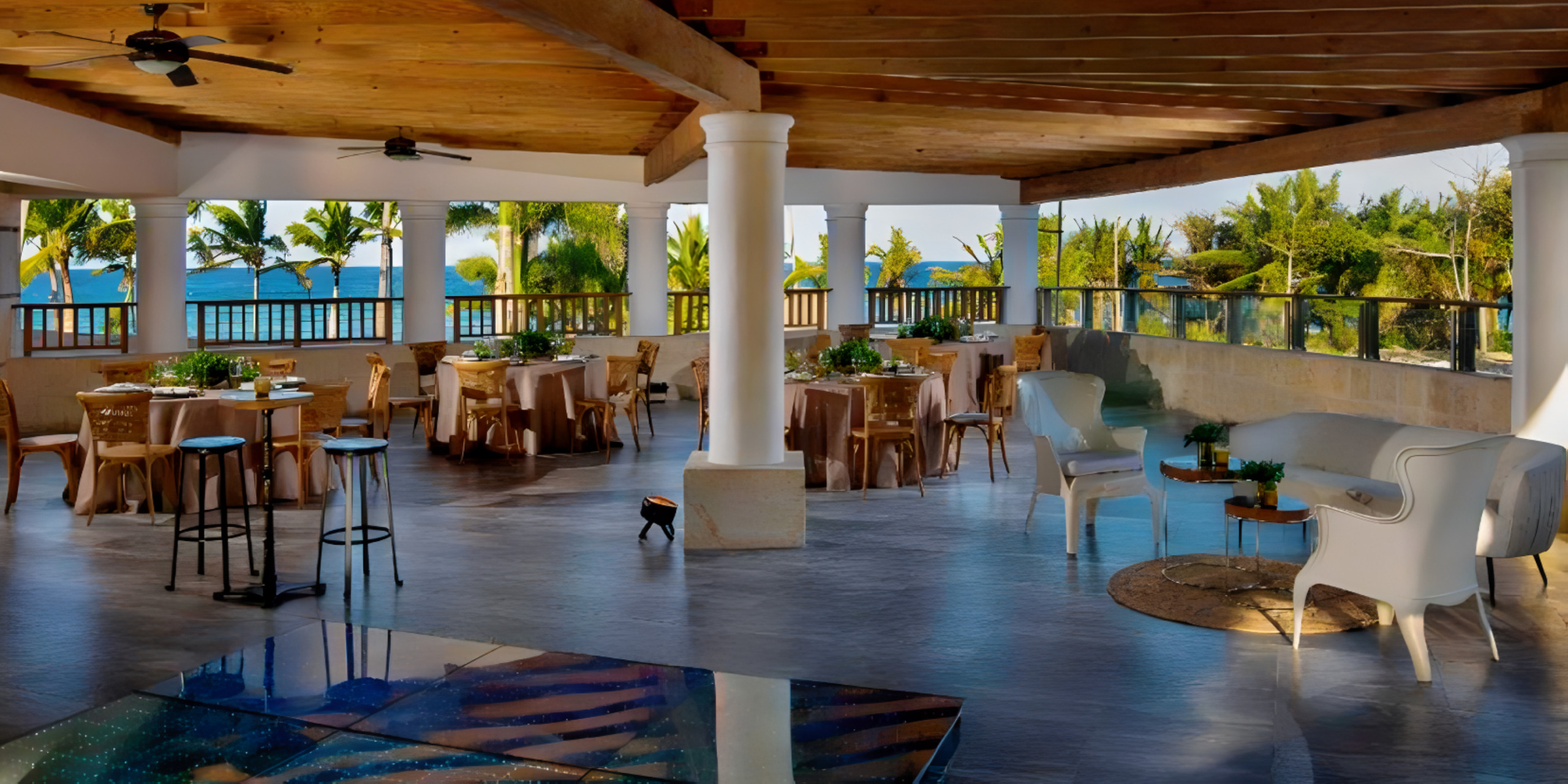 A destination wedding restaurant with tables and chairs overlooking the ocean.