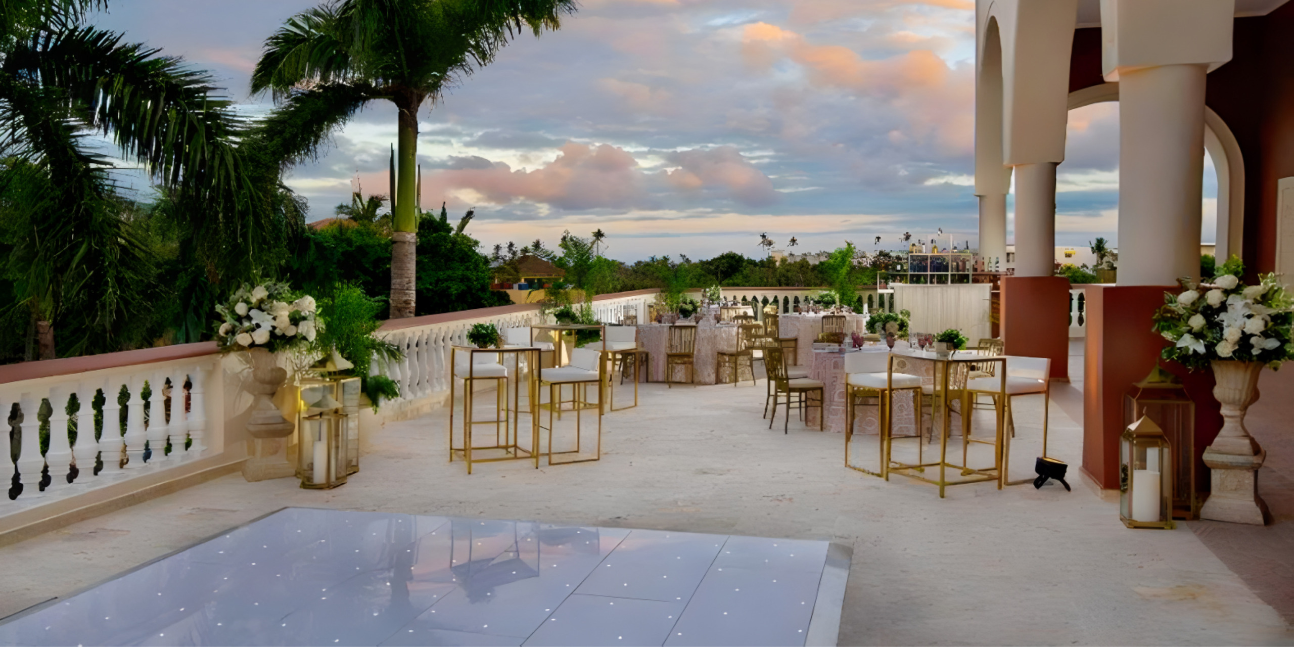 A destination wedding reception set up on a balcony overlooking palm trees.