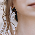 A woman wearing a pair of earrings with white beads for her wedding.