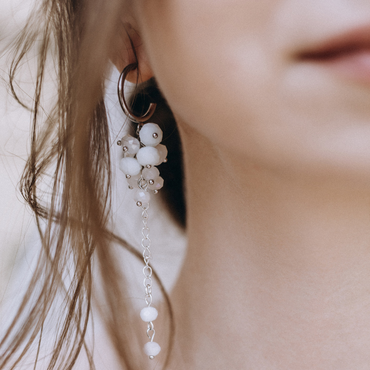 A woman wearing a pair of earrings with white beads for her wedding.