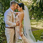 A bride and groom embrace in front of a tropical garden during their Destify wedding.