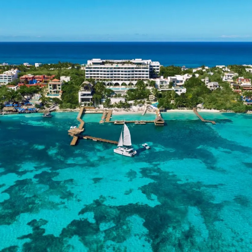 An aerial view of Impression Isla Mujeres by Secrets with a sailboat in the water.