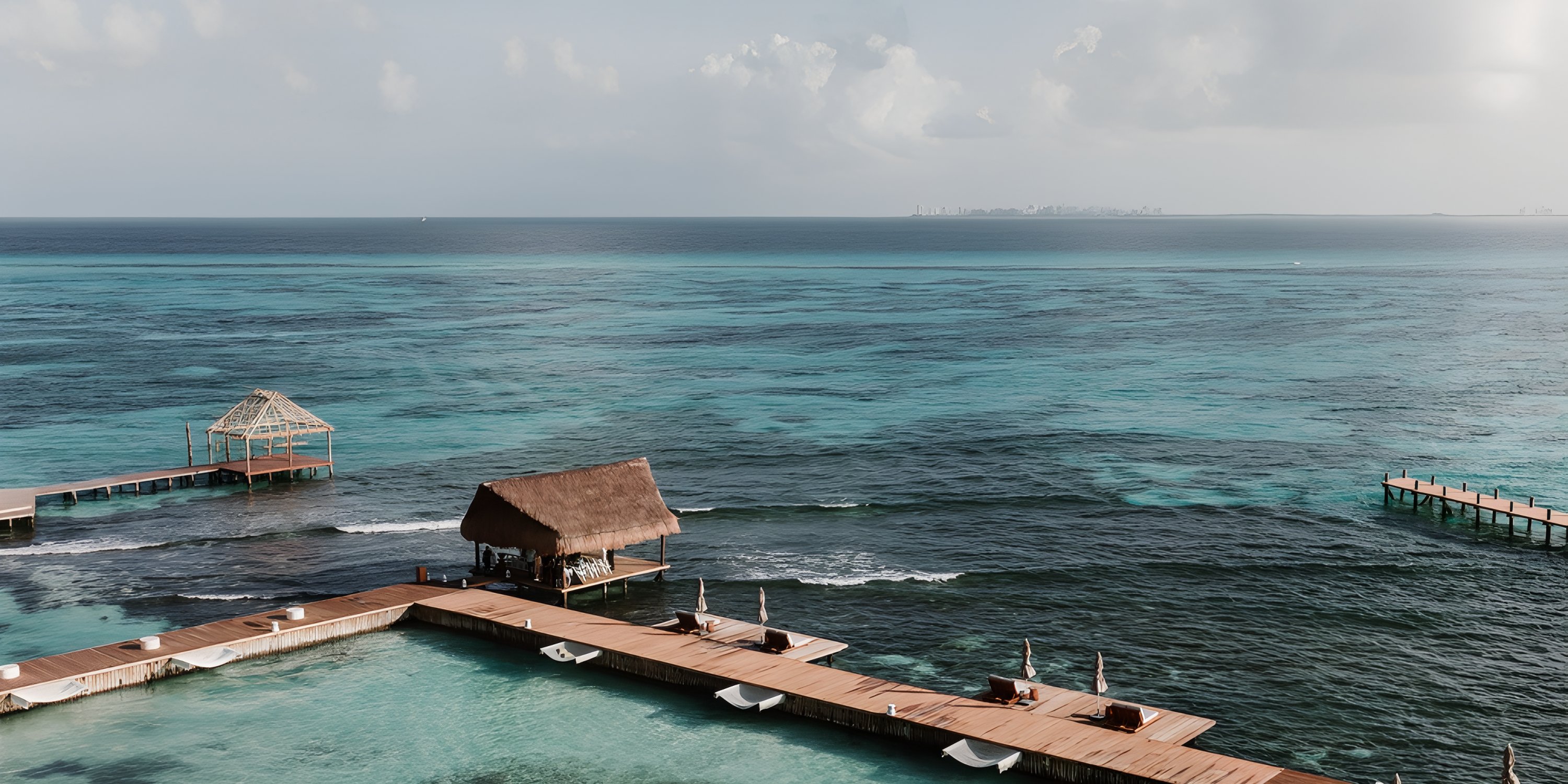 Thatched huts on wooden piers over blue ocean under a cloudy sky, ideal for a destination wedding.