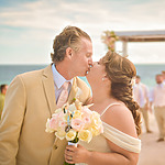 A bride and groom kissing on the beach during their destination wedding.