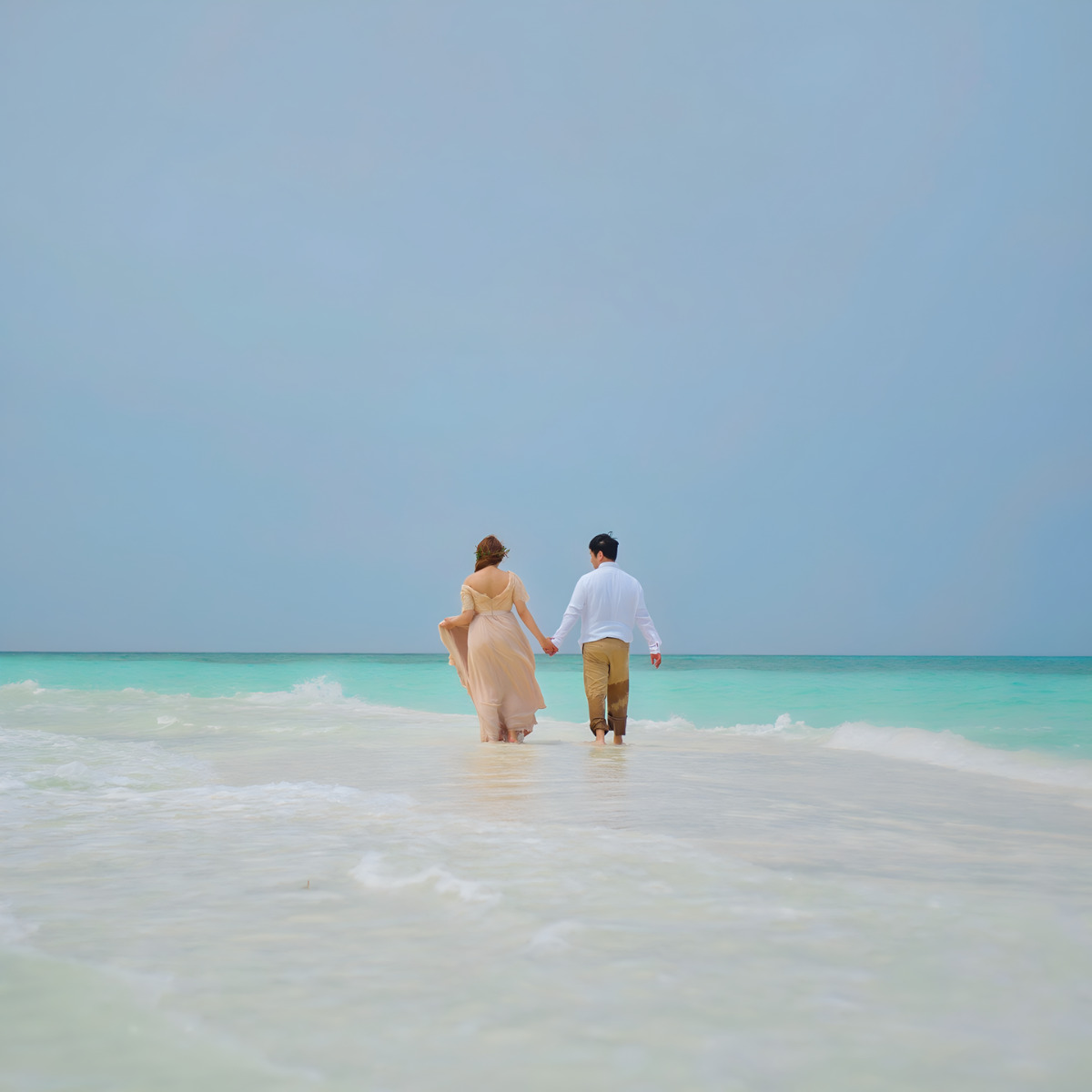 A couple strolling on a sandy beach by the ocean.