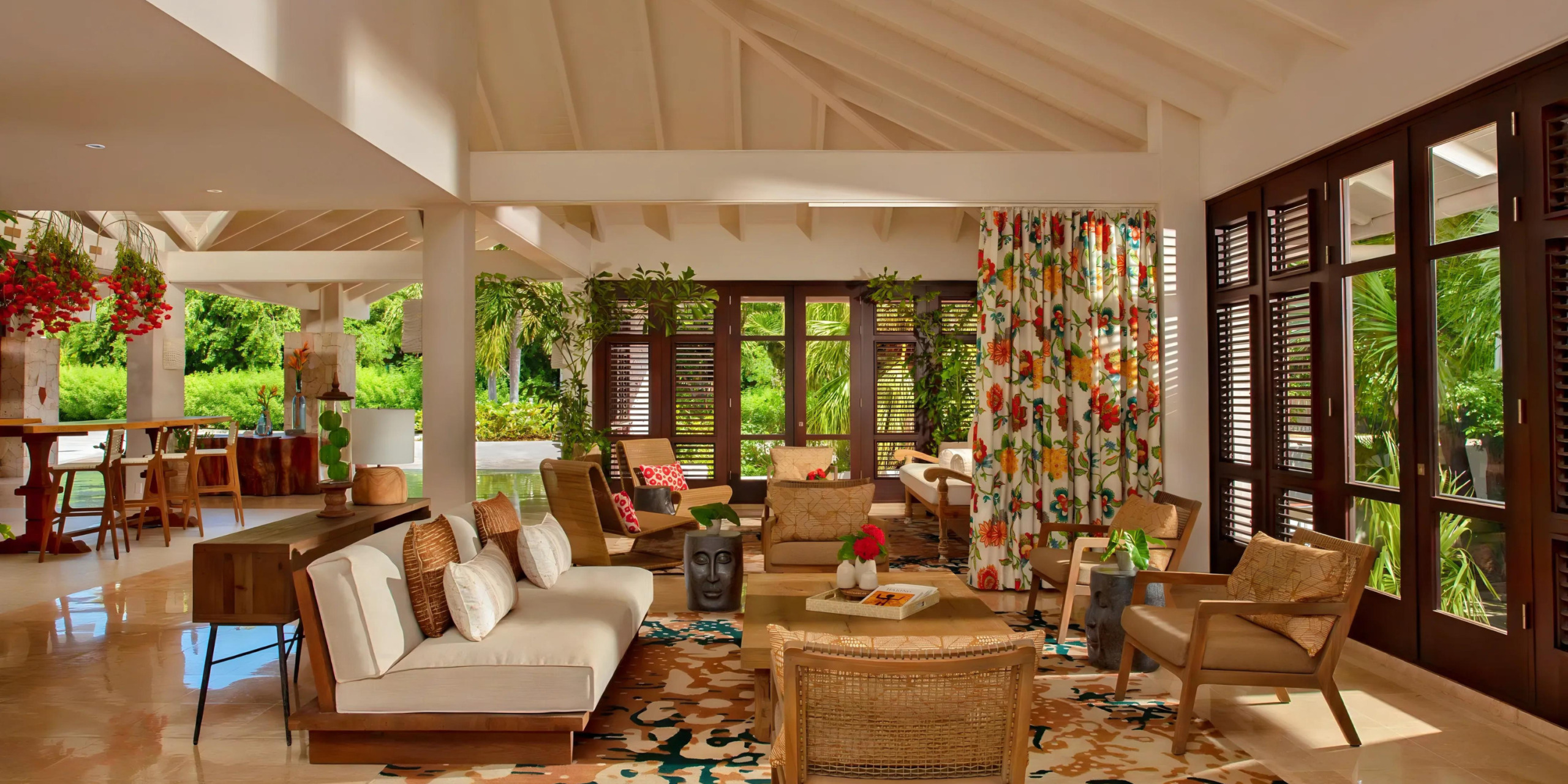 A living room with large windows, Zoëtry Curaçao Resort & Spa furniture, and decor.