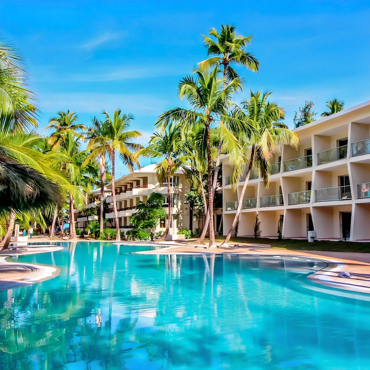A swimming pool surrounded by palm trees at a resort, perfect for a destination wedding.