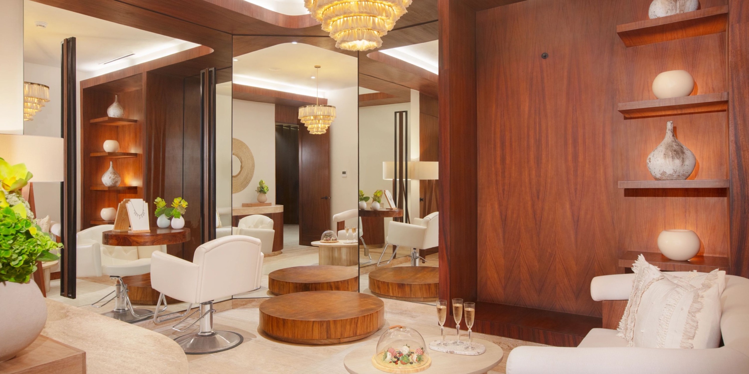 Step into the opulent surroundings of Impression Isla Mujeres by Secrets, featuring mirrors, chandeliers, elegant white seating, and sophisticated wooden accents. Glasses of champagne and exquisite floral arrangements enhance the luxurious ambiance.