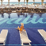 A bride sits in a lounge chair next to a swimming pool, planning her destify wedding.