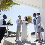 A bride and groom standing on a wooden deck at their wedding.