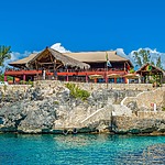 A wedding restaurant sits on top of a rocky cliff overlooking the ocean.