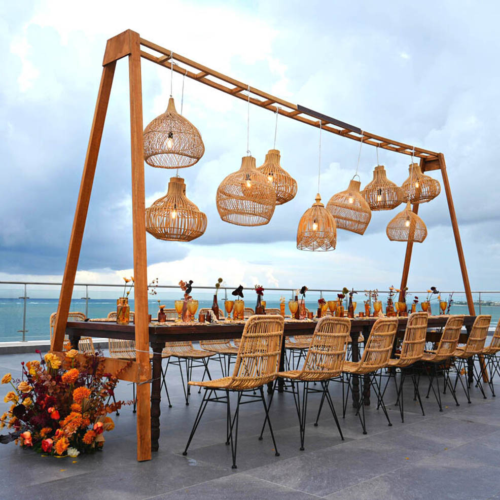 A wicker table and chairs set up on a balcony overlooking the ocean.