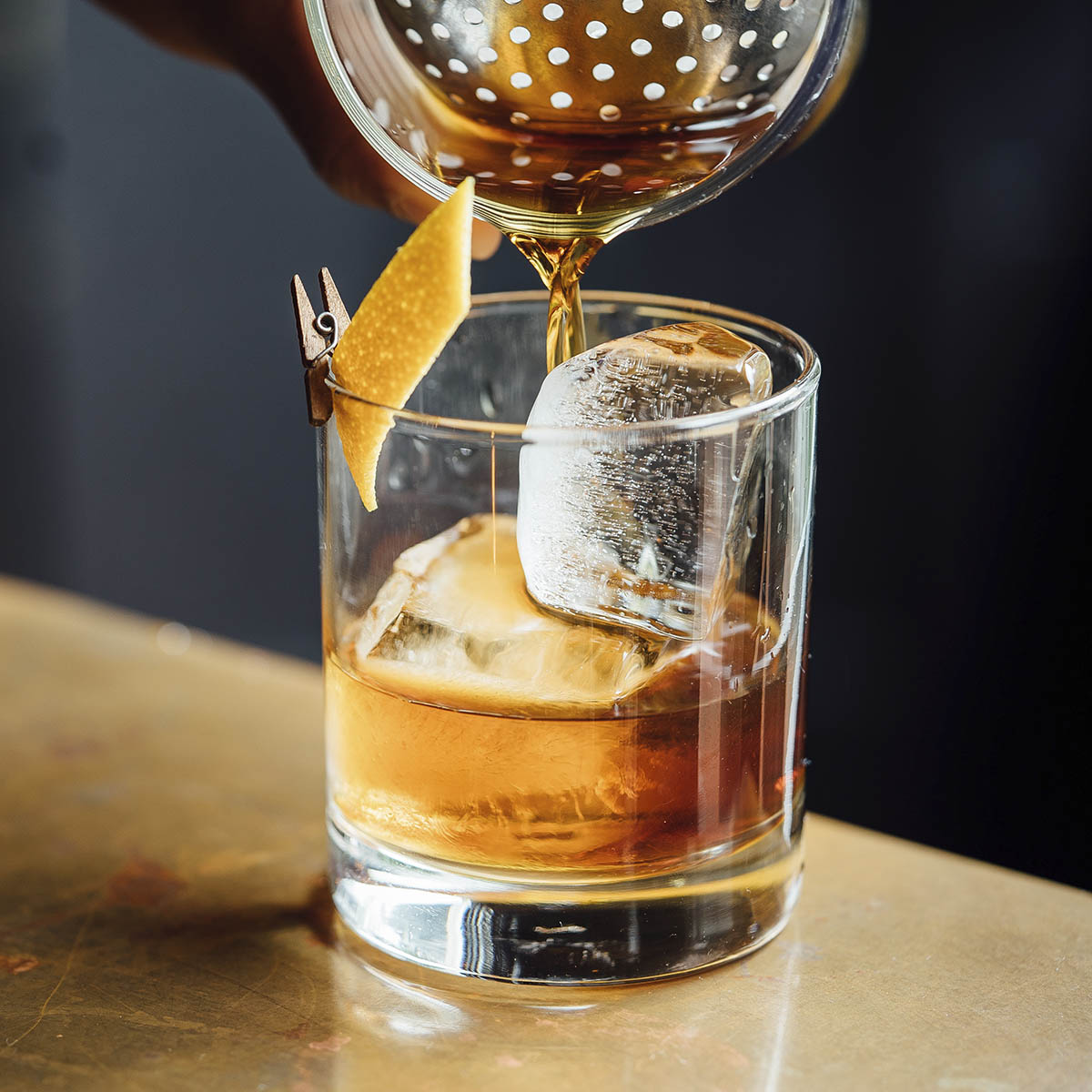 An old fashioned from the bar service for a wedding being poured into a glass.