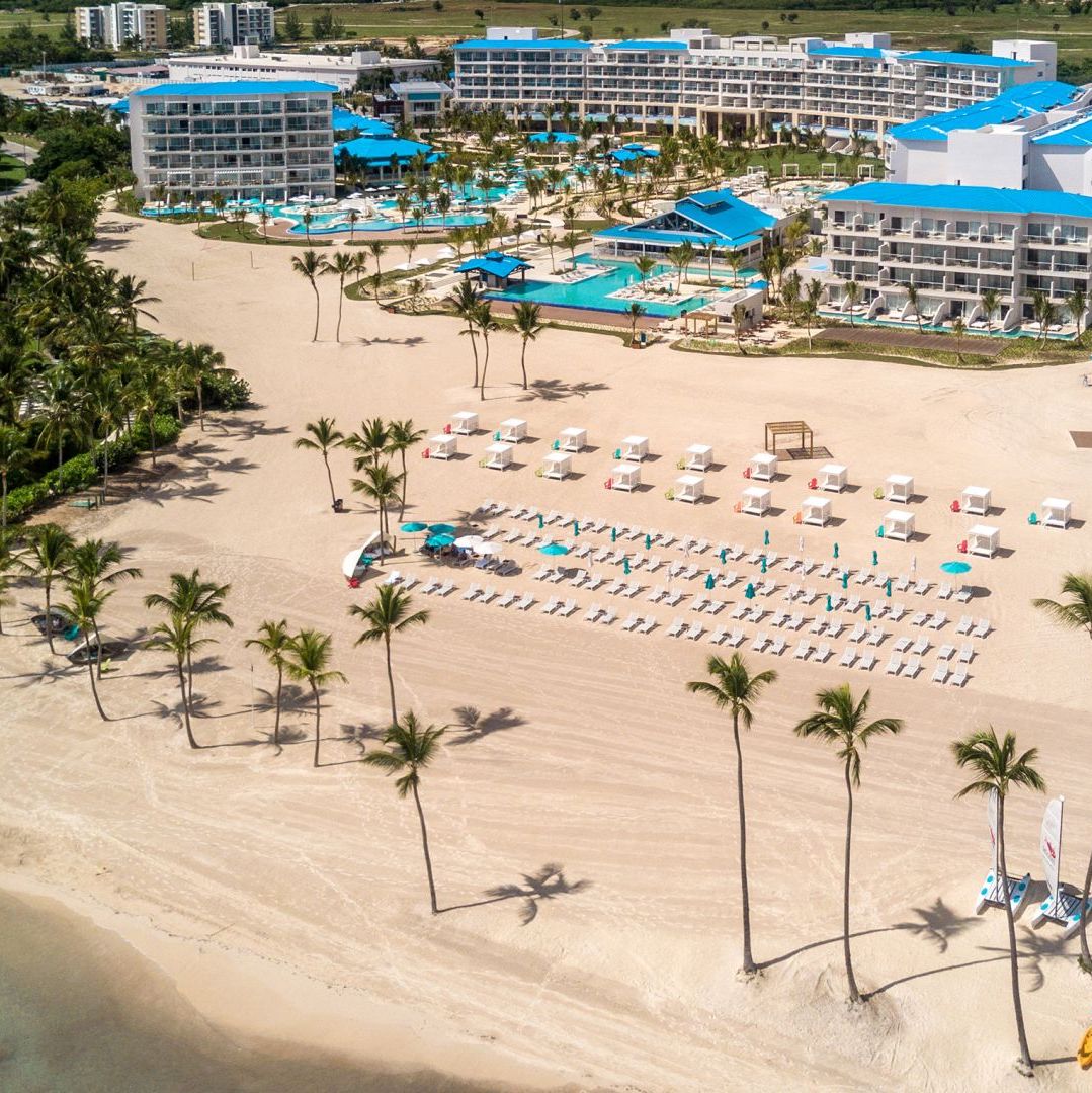 An aerial view of a resort hosting a beach wedding with palm trees.