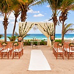A beach wedding ceremony set up in front of palm trees, perfect for Mexico wedding packages.