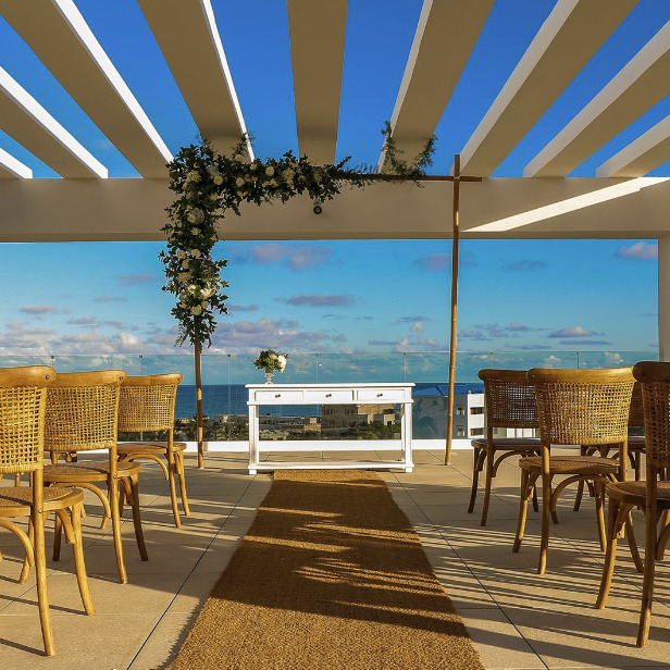 A wedding ceremony set up on a balcony overlooking the ocean.