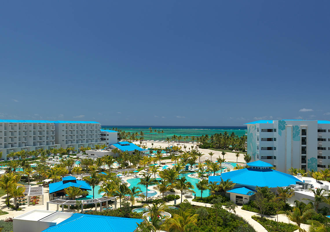 An aerial view of Margaritaville Island Reserve Cap Cana - Hammock with blue roofs and a pool.