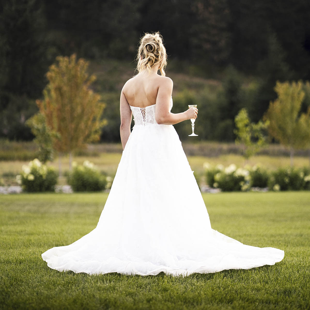 A bride in a destify wedding dress standing in a grassy field.
