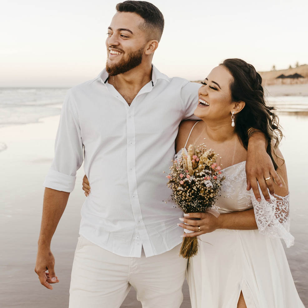 A bride and groom laughing at sunset during their wedding at Secrets Bahia Mita beach.