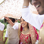 A bride and groom smiling while holding a wedding veil at an Indian wedding in Mexico.