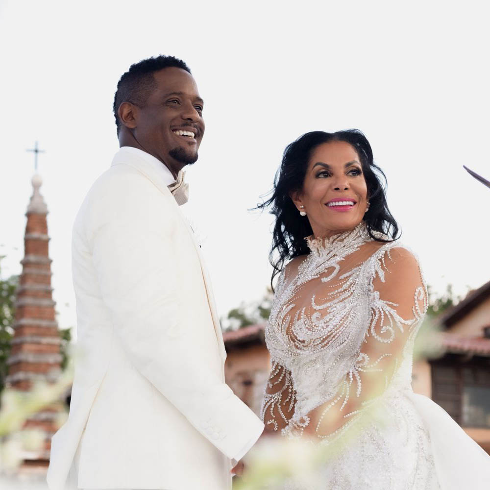 A bride and groom smiling in front of a church, looking as radiant as Blair Underwood.