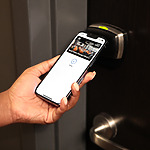 A person holding a phone while implementing safety measures and holding a door handle.