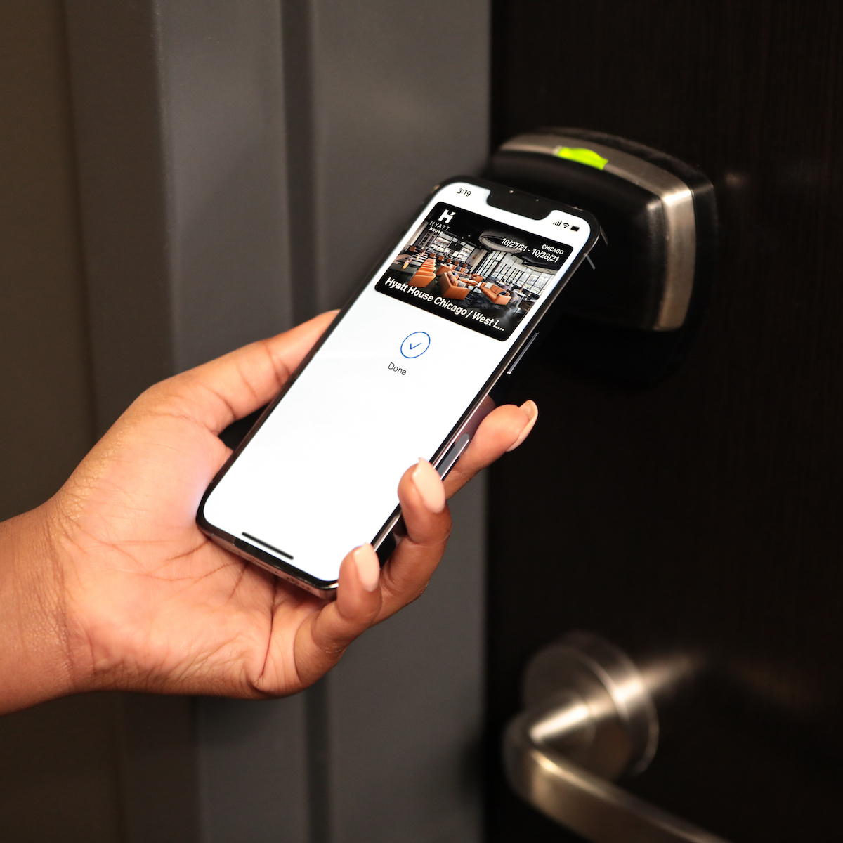 A person holding a phone while implementing safety measures and holding a door handle.