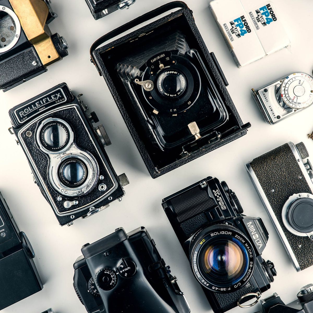 A collection of vintage cameras arranged on a white surface, perfect for capturing timeless moments at a wedding or destination wedding.