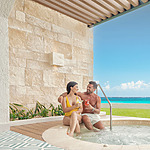 A man and woman relaxing in a hot tub at Hilton Cancun Mar Caribe, with a view of the ocean.