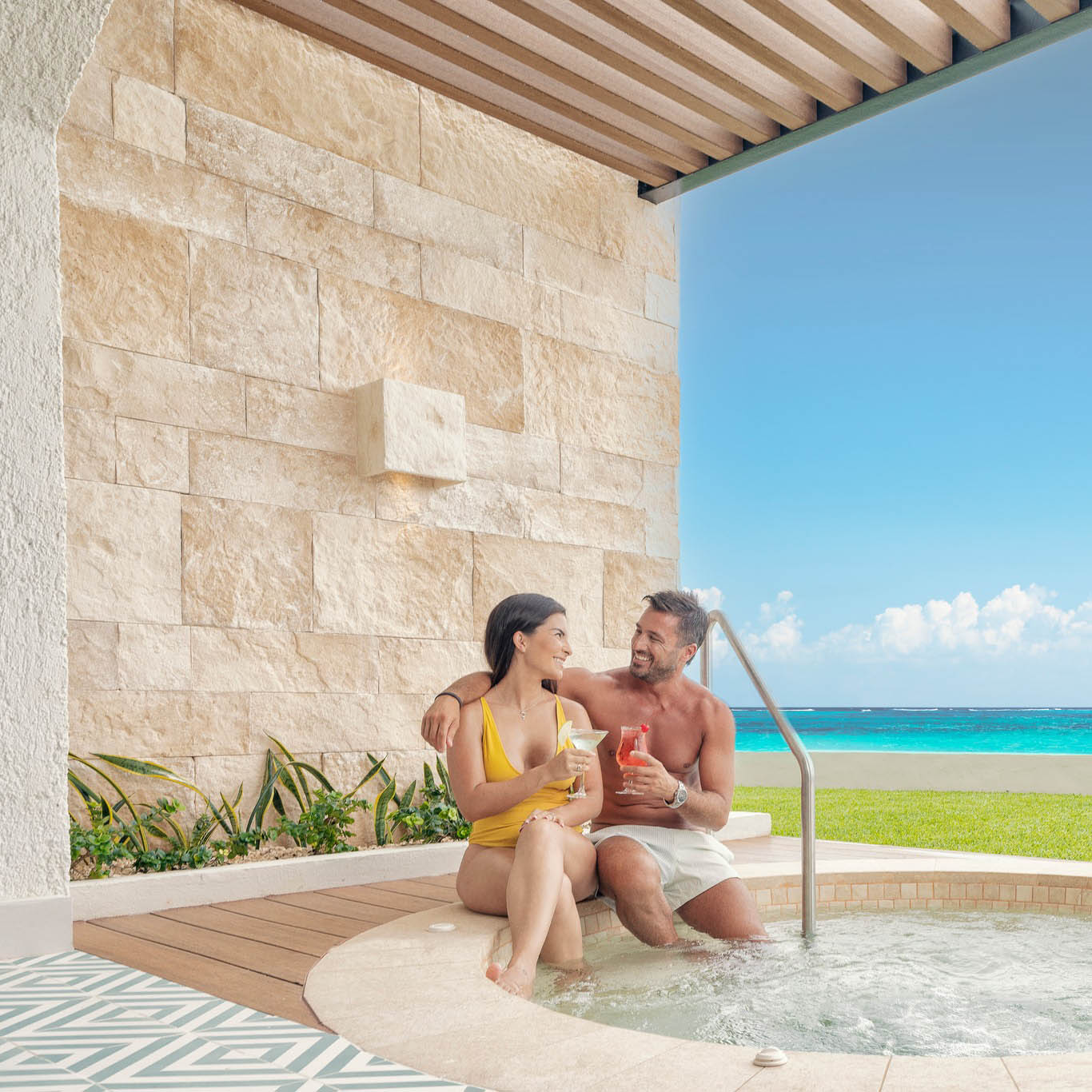 A man and woman relaxing in a hot tub at Hilton Cancun Mar Caribe, with a view of the ocean.
