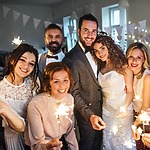 A group of people celebrating with sparklers at a wedding.