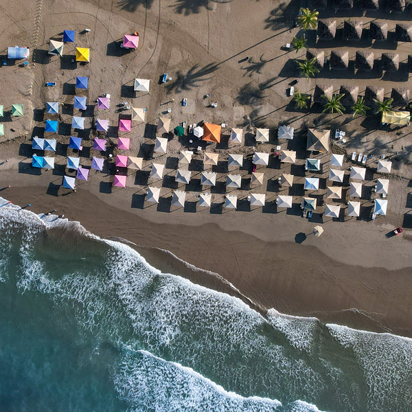 An aerial view of a beach with colorful umbrellas.