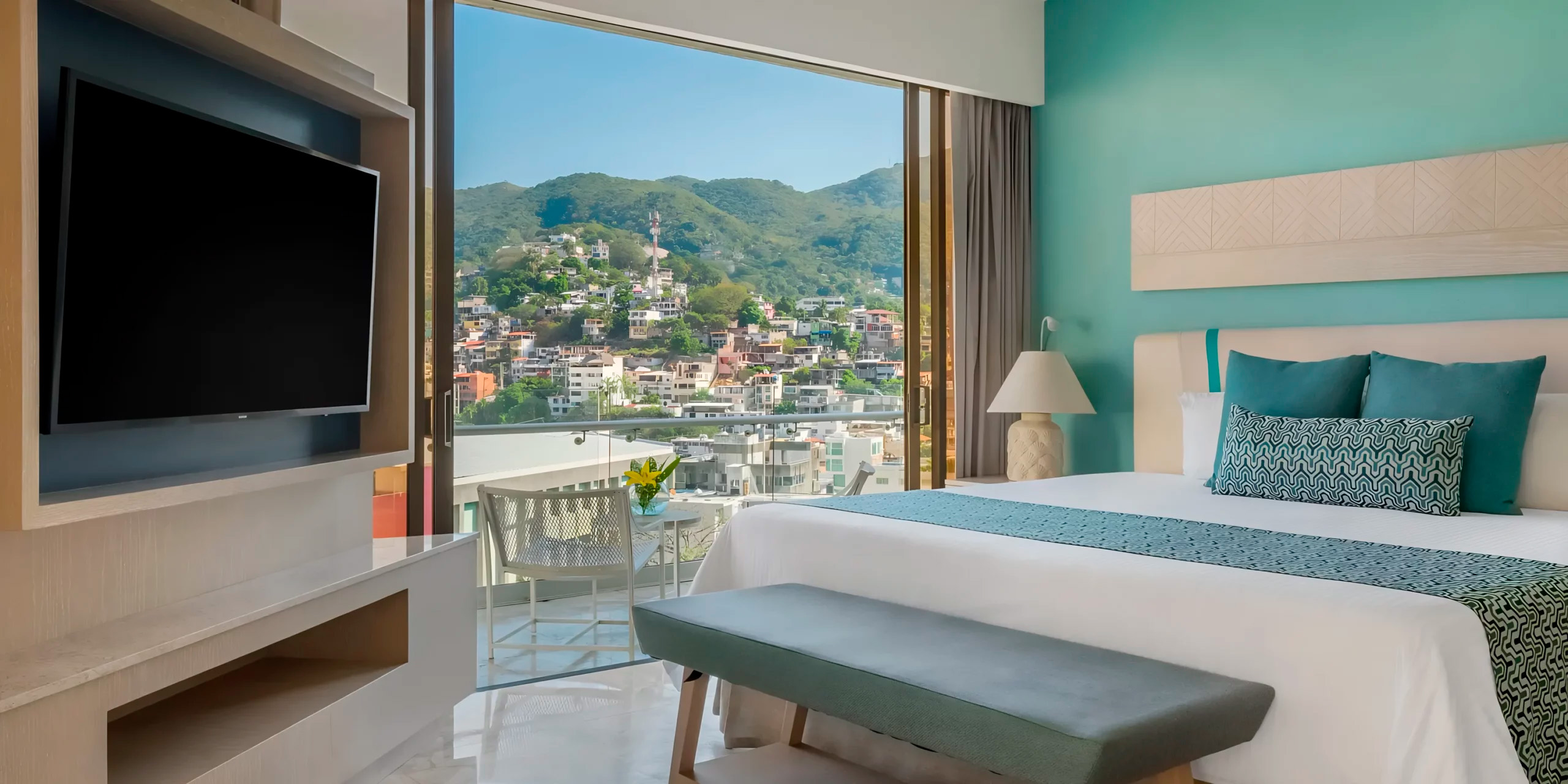 Experience the allure of Modern Dreams Acapulco, where our room features a large window offering breathtaking views of the city and lush green hills—an idyllic setting for your destination wedding.