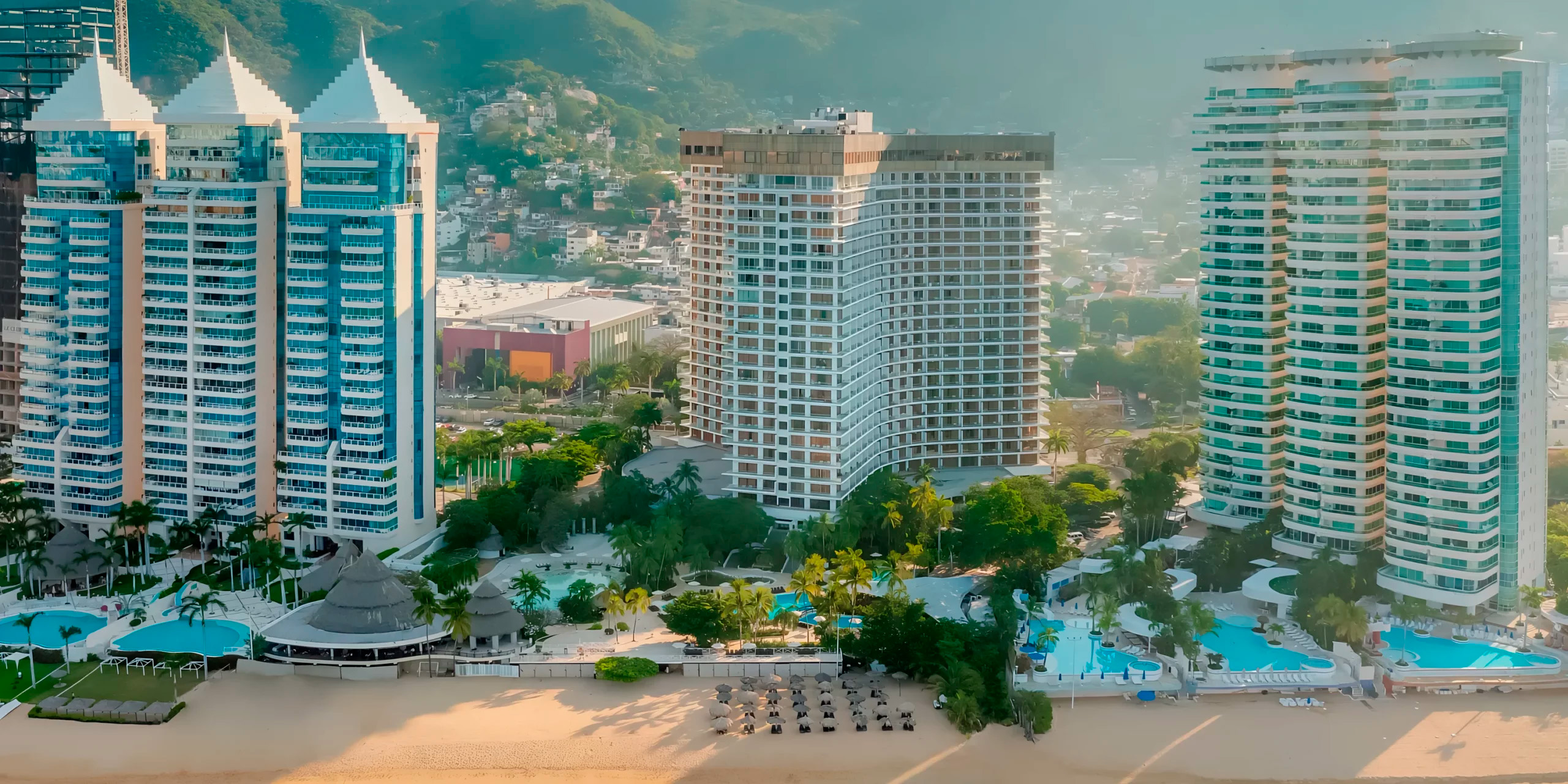 Dreams Acapulco Resort & Spa: A stunning beachfront high-rise adorned with lush greenery and inviting beach chairs, perfect for an unforgettable destination wedding.